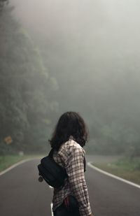 Rear view of woman standing on road