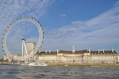 Ferris wheel in front of river against sky
