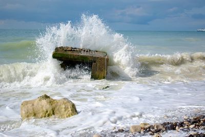 Waves splashing on sea against sky