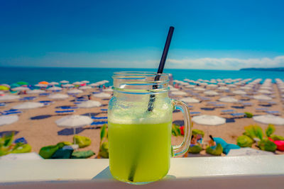 Drink on table against blue sea