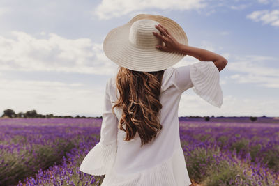 Rear view of woman wearing hat while standing at farm