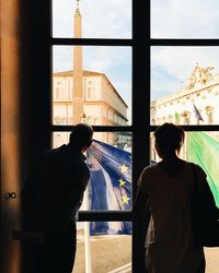 Friends looking through window in city at home