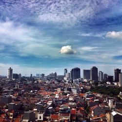 View of cityscape against cloudy sky