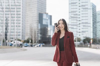Woman standing on mobile phone in city