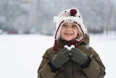 Child enjoying winter. the boy holds a heart made of snow in his hands in winter day. love concept.