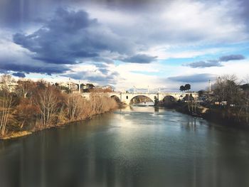 Bridge over river in city against sky