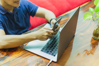 Midsection of man using laptop on table