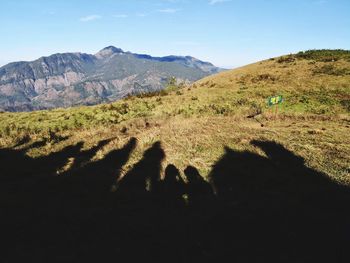 Shadow of people on mountain against sky