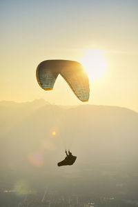 Paraglider silhouette flying at sunset