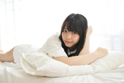 Portrait of young woman lying on bed at home