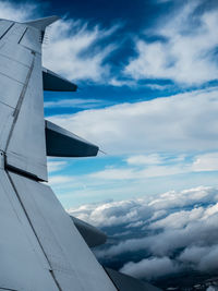 Close-up of airplane wing against cloudy sky