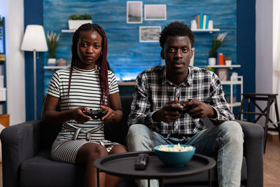 Friends looking away while sitting on sofa