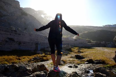 Rear view of man standing on rock against sky