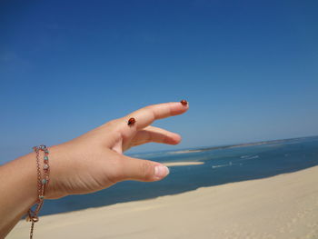 Woman hand on beach against clear sky