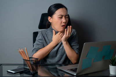 Young woman using mobile phone while sitting on table