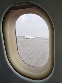 Airplane flying over airport runway against sky