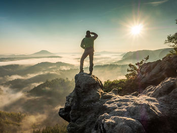 Man standing on rock at mountain against sky