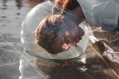 Close-up of woman wearing glass container at lake