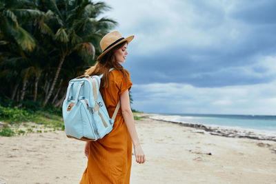 Woman standing at beach against sky