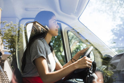 Side view of confident young female owner driving food truck