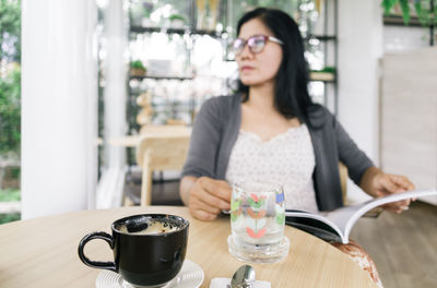 Woman looking away while sitting at table in cafe