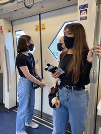 Women wearing masks standing in subway train