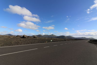 Road by mountains against sky