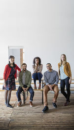 Portrait of happy business people against wall at creative office