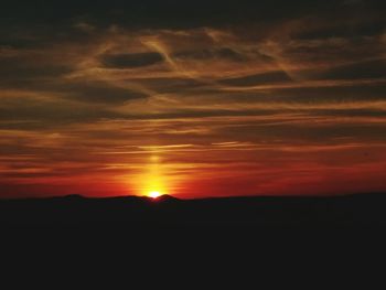 Scenic view of silhouette landscape against orange sky