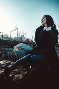 Side view of woman looking away against sky