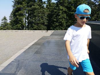 Cute boy walking on road during sunny day