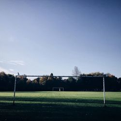 Scenic view of soccer field against clear blue sky