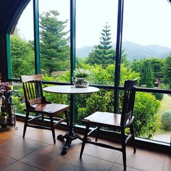 Empty chairs and tables against sky seen through window