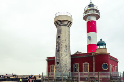Low angle view of lighthouse against buildings
