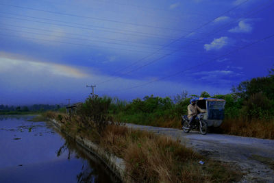 Horse riding motorcycle on road against sky
