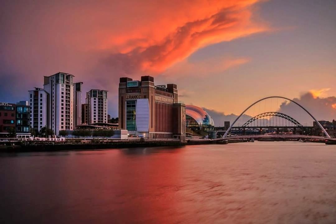 BRIDGE OVER RIVER WITH BUILDINGS IN BACKGROUND