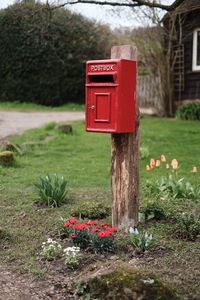 Red mailbox on wooden post in field