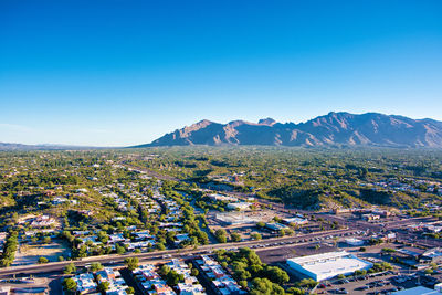 Aerial view of townscape and mountains against clear blue sky
