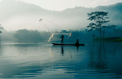 Silhouette fisherman fishing in lake