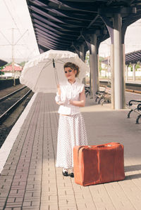 Portrait of young woman standing on railroad station platform