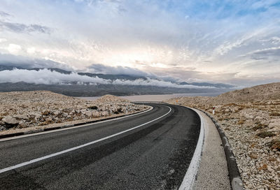Empty road with with dividing line. rocky terrain, beautiful sky.