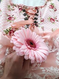 Cropped hand holding pink flower on dress