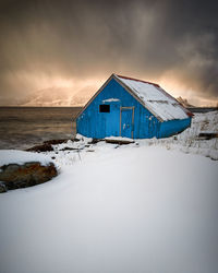 Blue boat house during a sunset blizzard, godøy, sunnmøre, møre og romsdal, norway.
