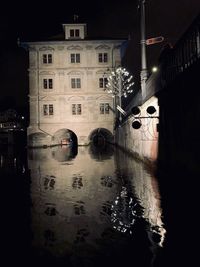 Reflection of illuminated bridge on canal in city at night