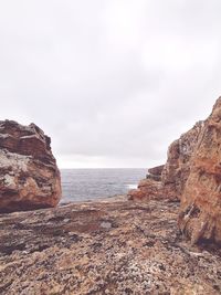 Rock formations by sea against sky