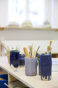 Various paintbrushes in containers on table at workshop