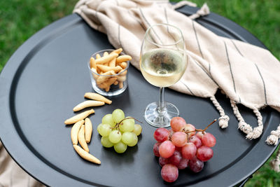 A glass of white wine with appetizers on the table.