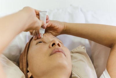 Asian woman uses eye drops for eye treatment