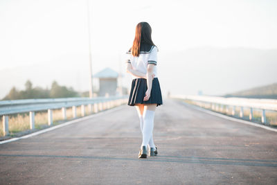 Rear view of woman standing on road