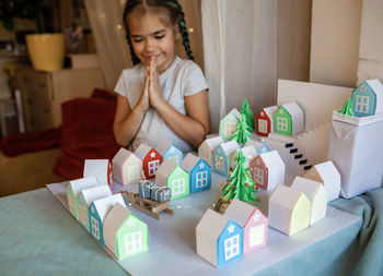 Origami advent calendar, paper craft. girl looking upon paper houses with number and paper tree